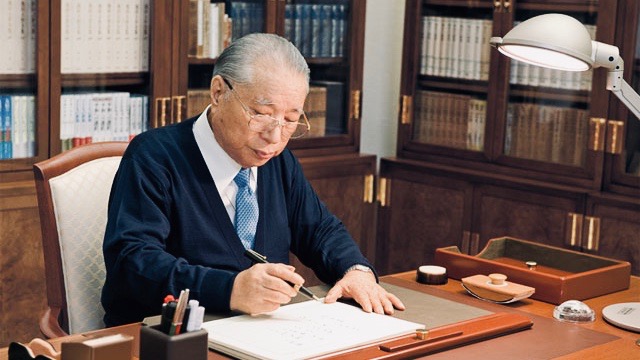 Daisaku Ikeda seated at his desk writing