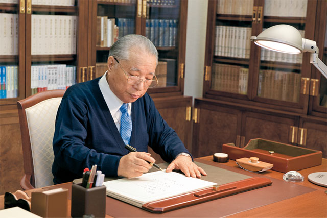 Daisaku Ikeda seated at his desk writing