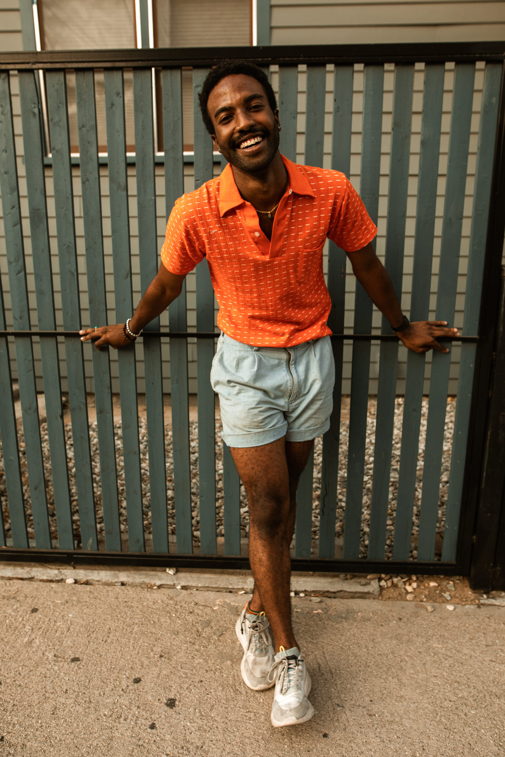 Guy standing along a fence smiling