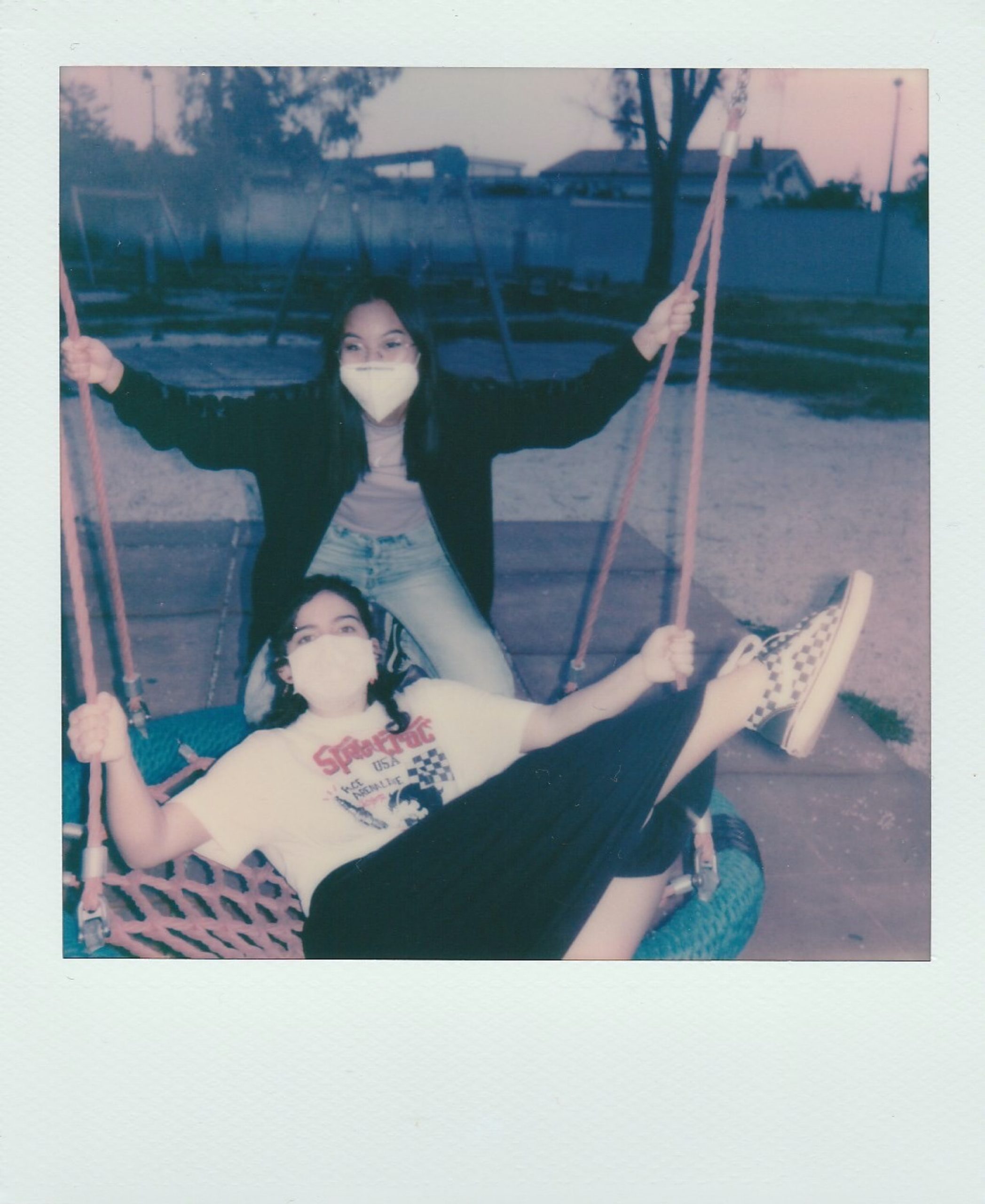 two girls wearing masks while hanging out in the park
