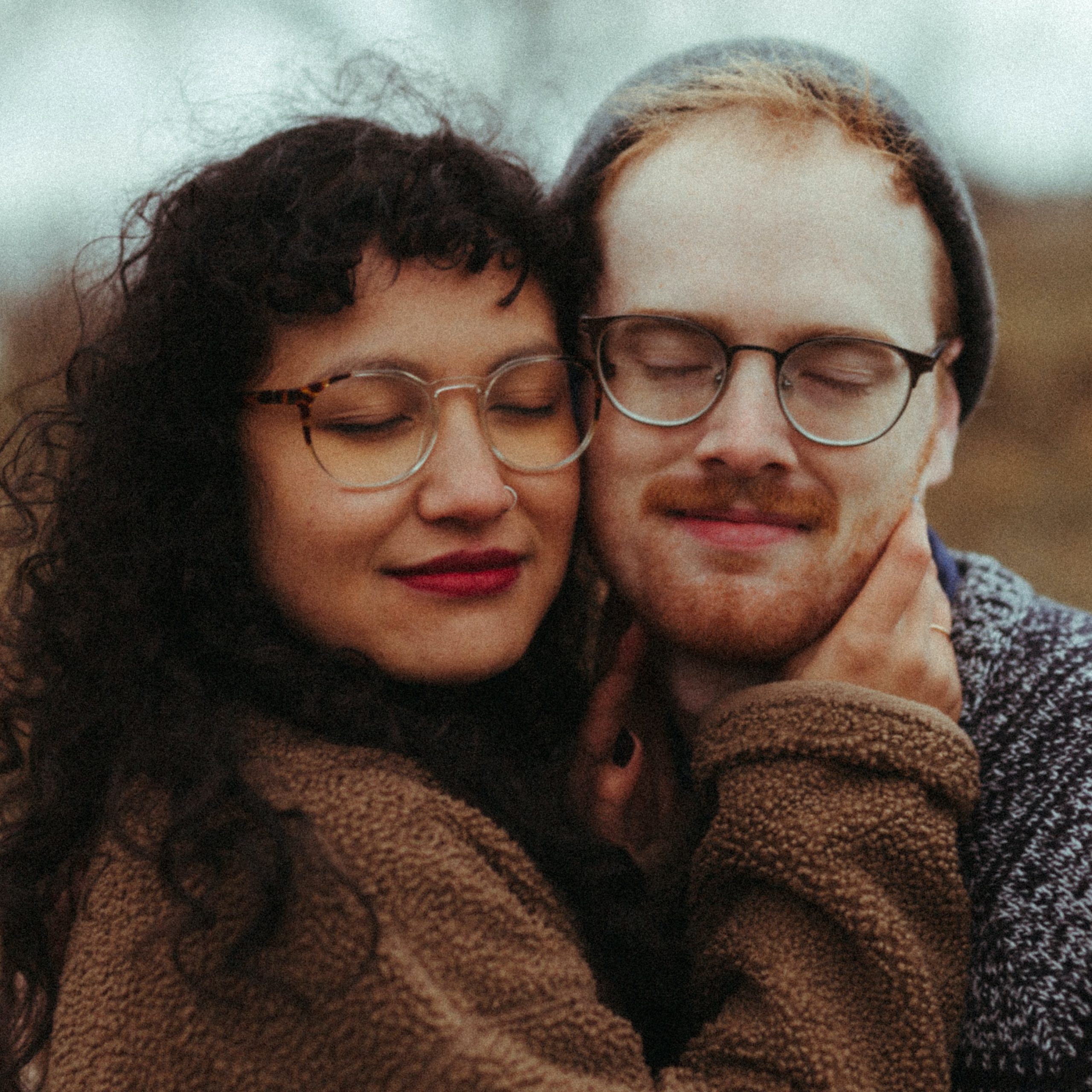 A couple with their cheeks pressed together and eyes closed with a slight smile.